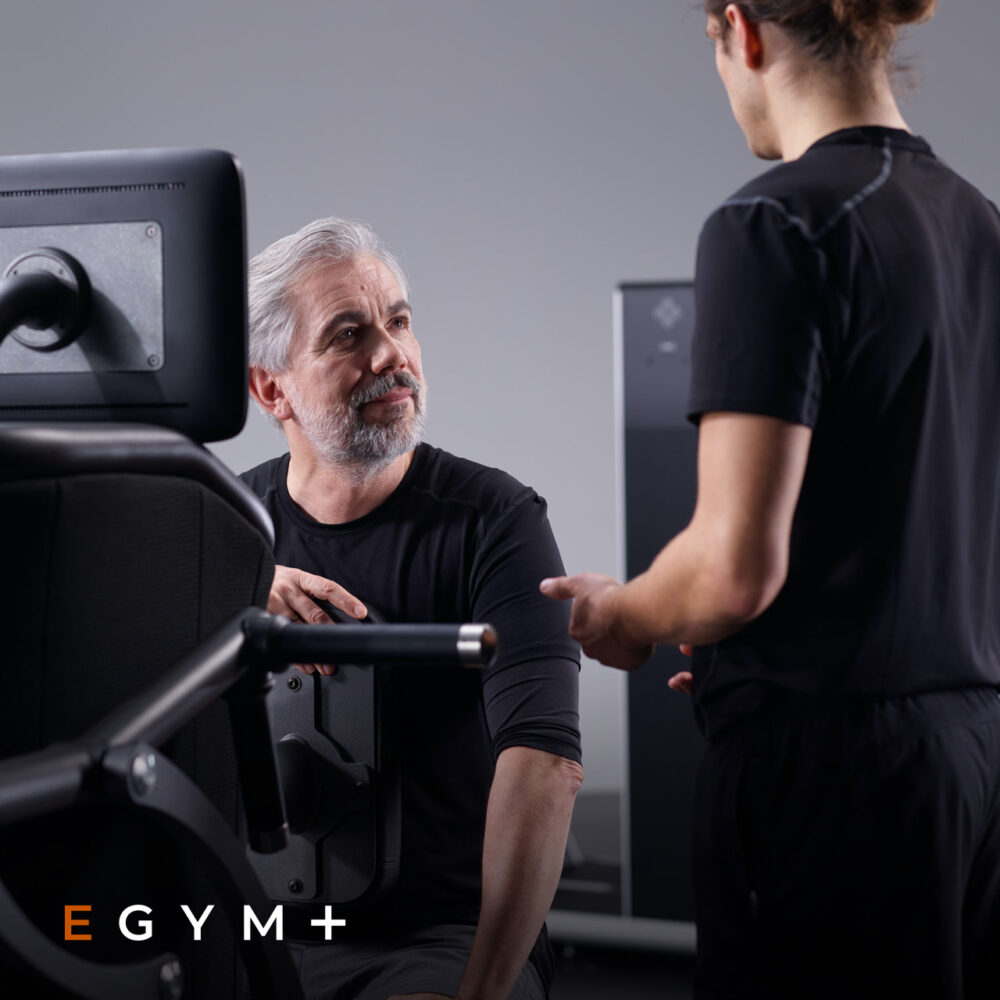 Trainer geeft instructie aan lid op egym toestel