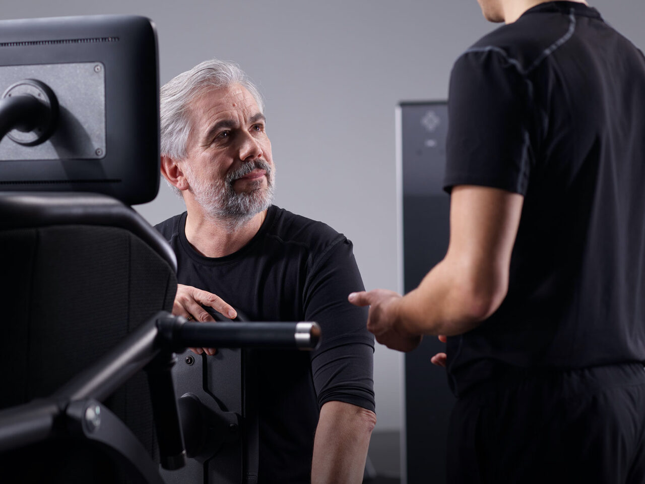 Trainer geeft instructie aan lid op egym toestel