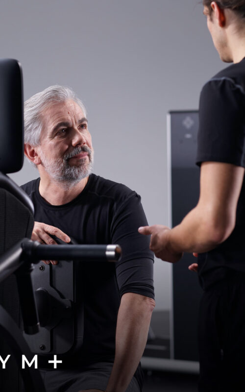 Trainer geeft instructie aan lid op egym toestel